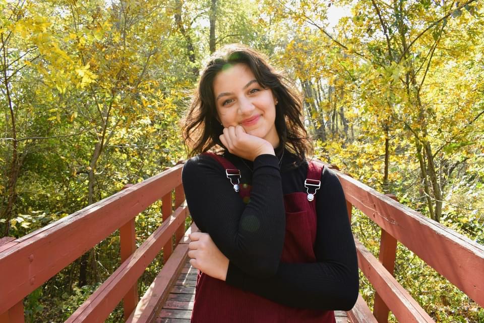 student posing in front of fall trees