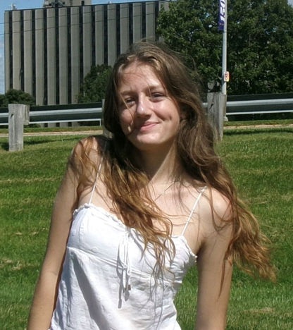 student standing and smiling in front of the bender dorm building 