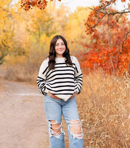 student posing in front of fall trees
