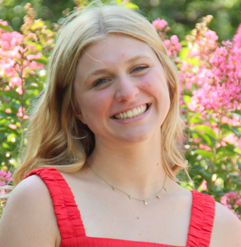 student smiling in front of flowers