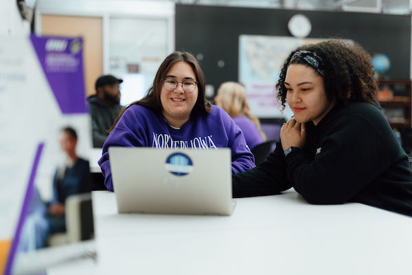 Two students looking at a laptop in a classroom